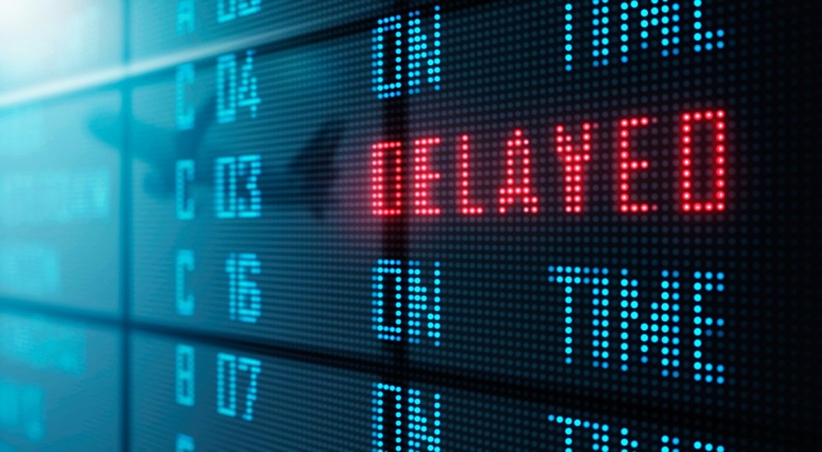 A departure board showing one line in red reading Delayed while the others read On Time