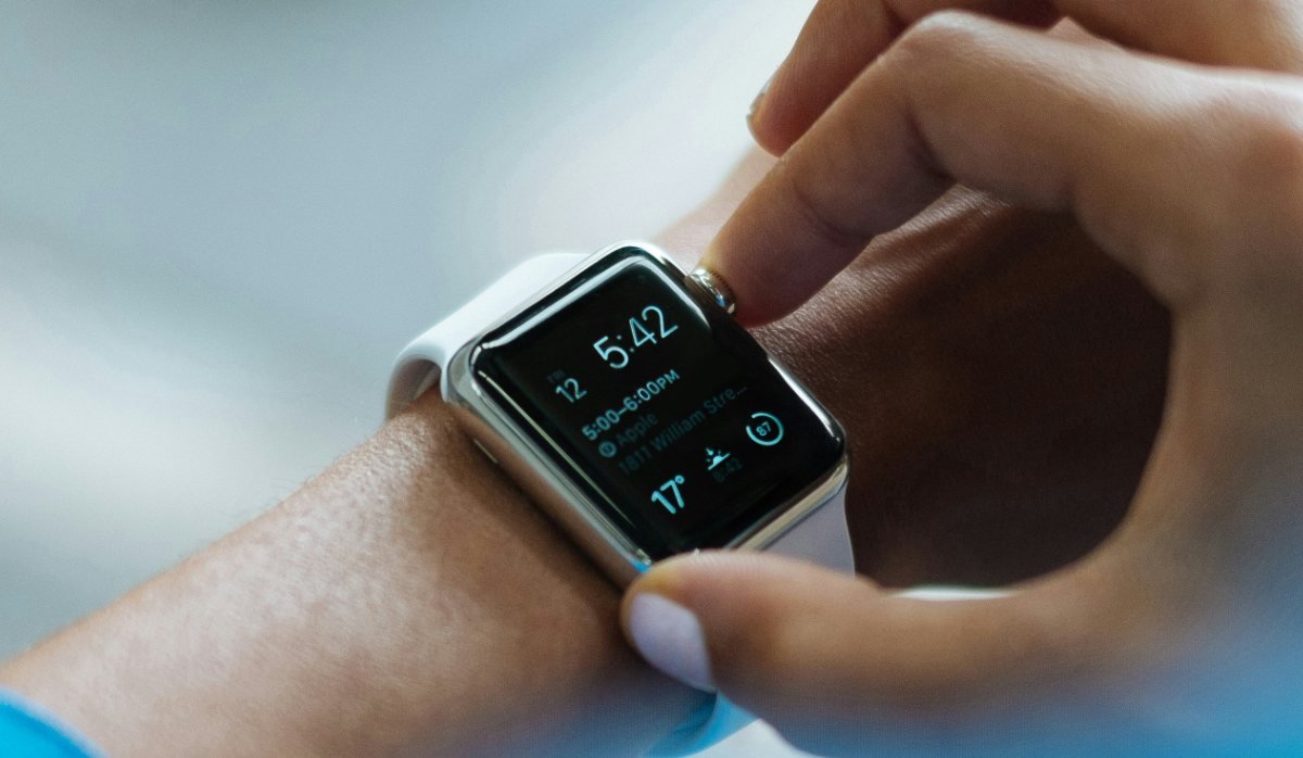 A hand tapping a smartwatch showing the time and an appointment
